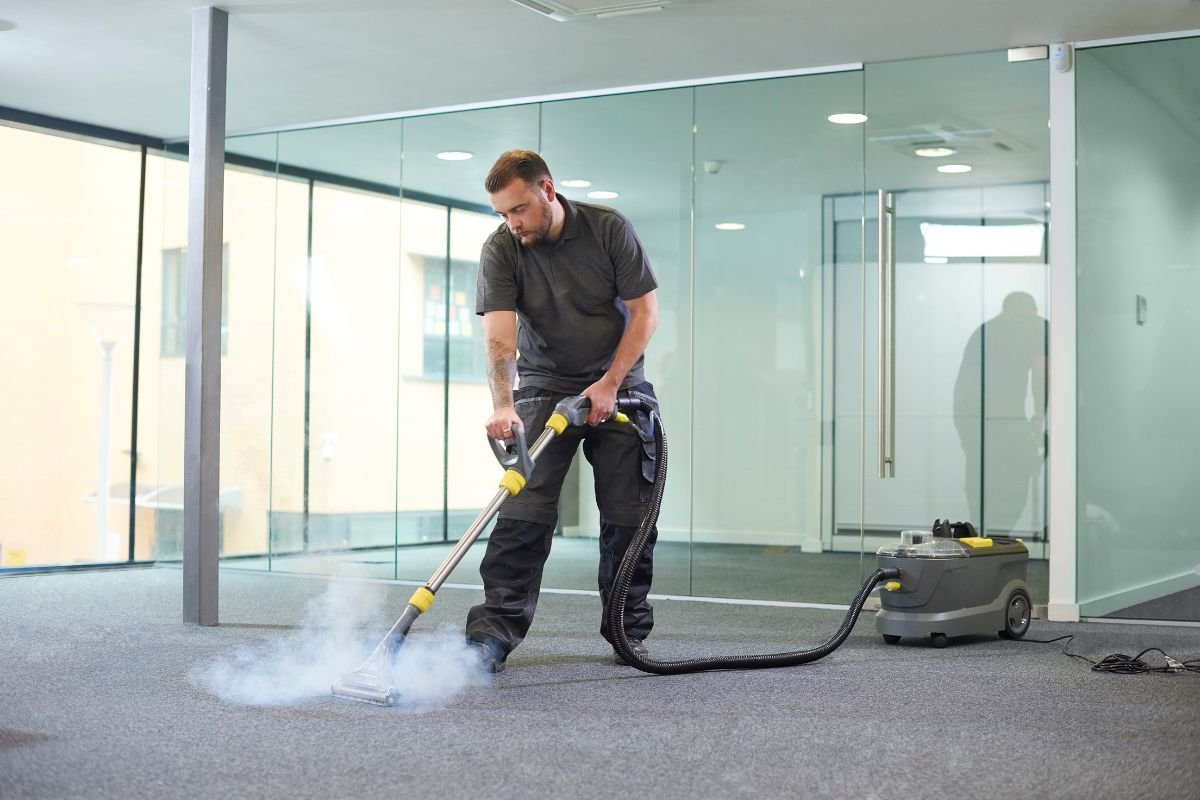 A man using a vacuum cleaner to clean a carpet, demonstrating effective carpet cleaning techniques.