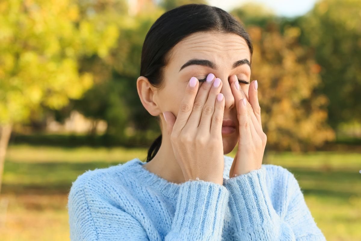  A woman covering her eyes with her hands, possibly reacting to allergens and dust from the carpet.
