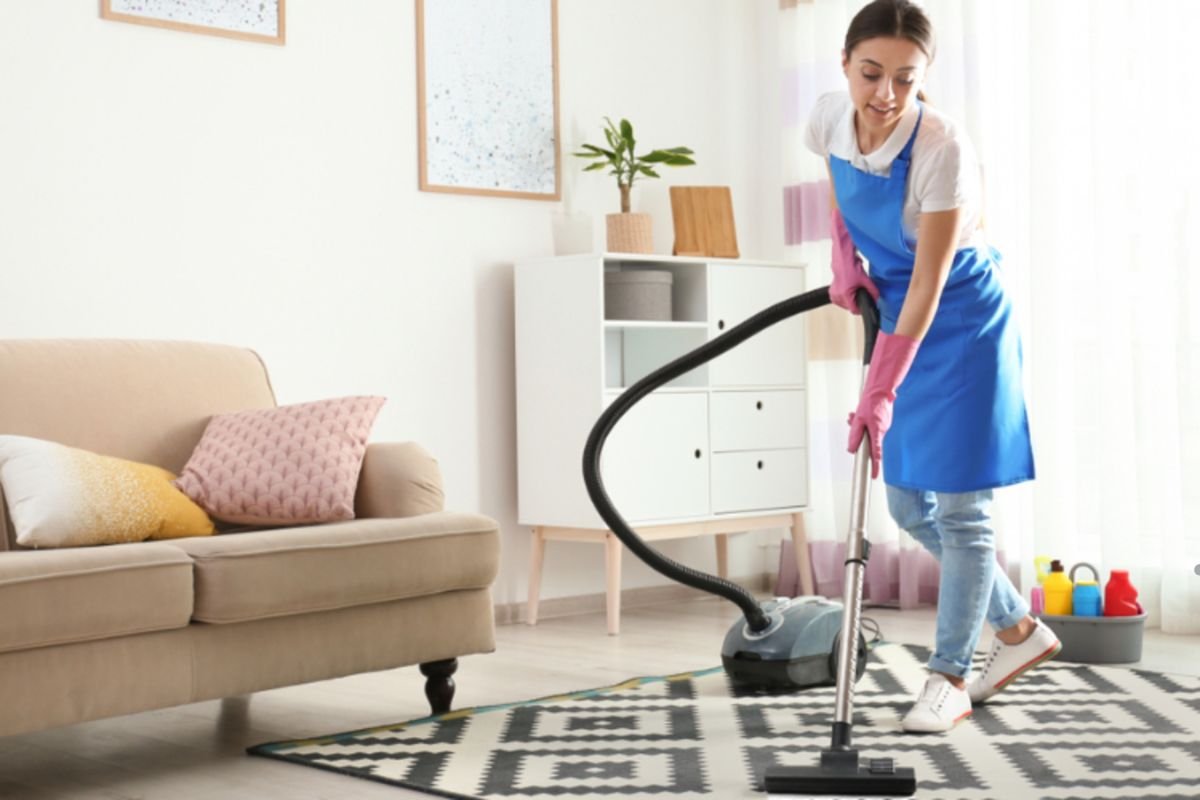  A woman in an apron cleans a room, promoting the concept of carpet alternatives for improved indoor air quality.