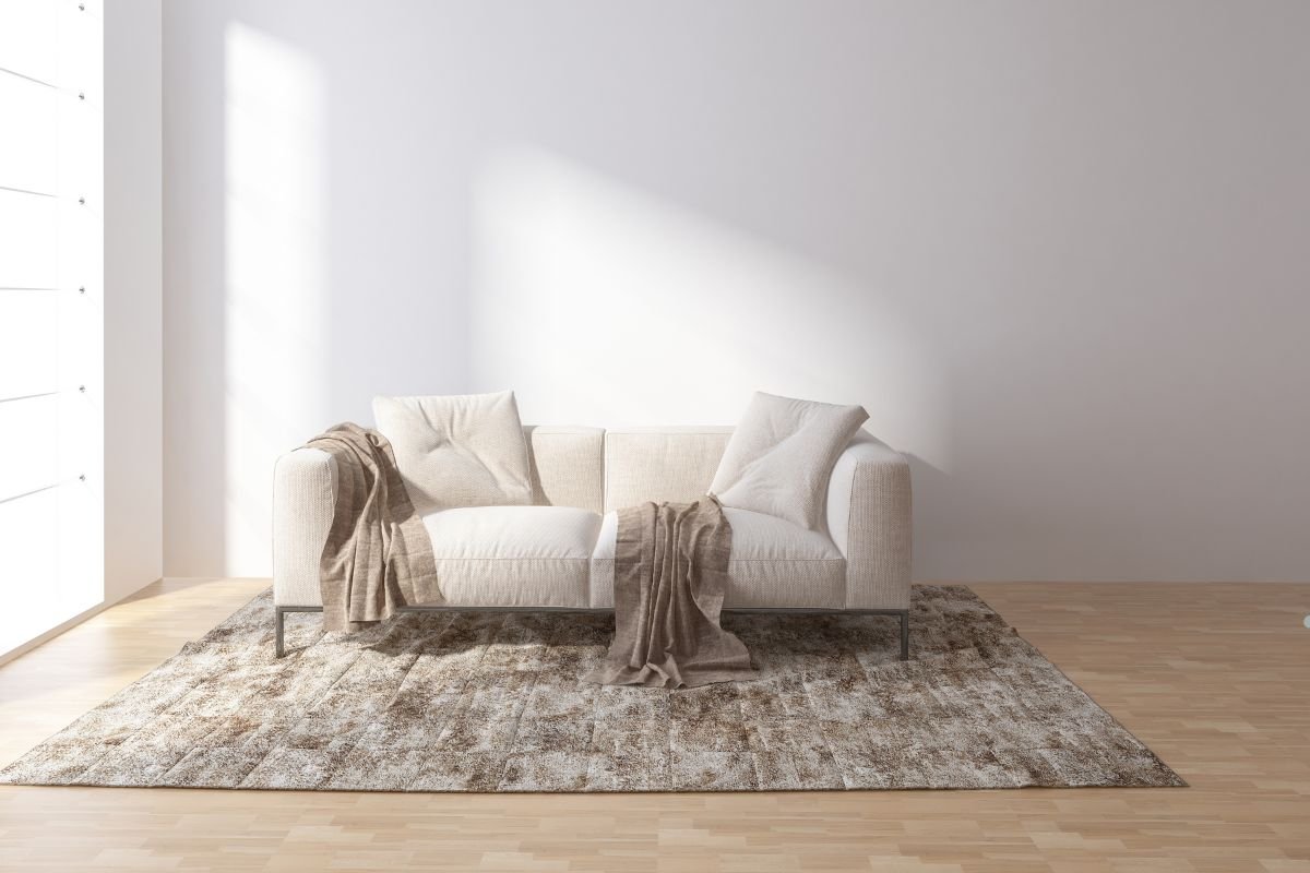 A white couch positioned in a room featuring a window, highlighting a bright and airy atmosphere. 