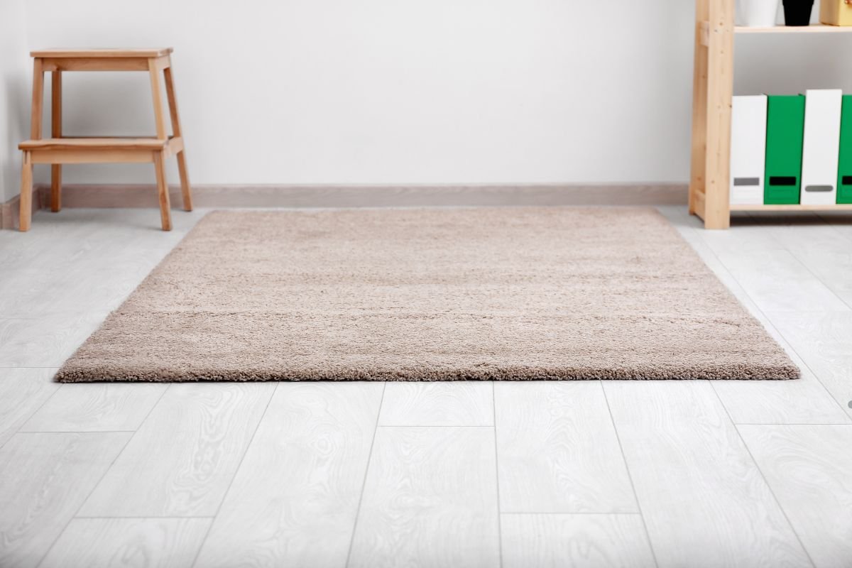 A cozy room featuring a rug, a chair, and a shelf, highlighting smarter carpet choices for Miami homes.